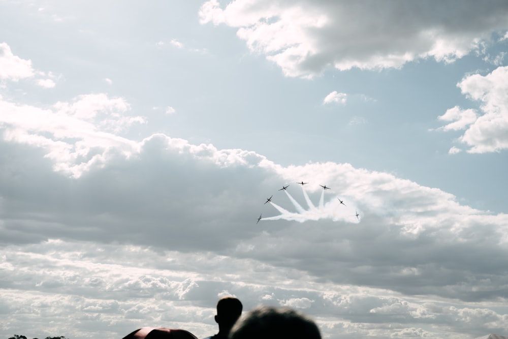 a group of people flying kites under a cloudy sky