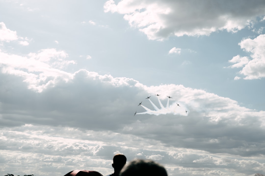 a group of people flying kites under a cloudy sky,