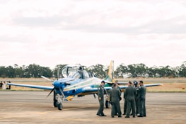 A group of diverse aviation ground staff smiling together near an airplane.