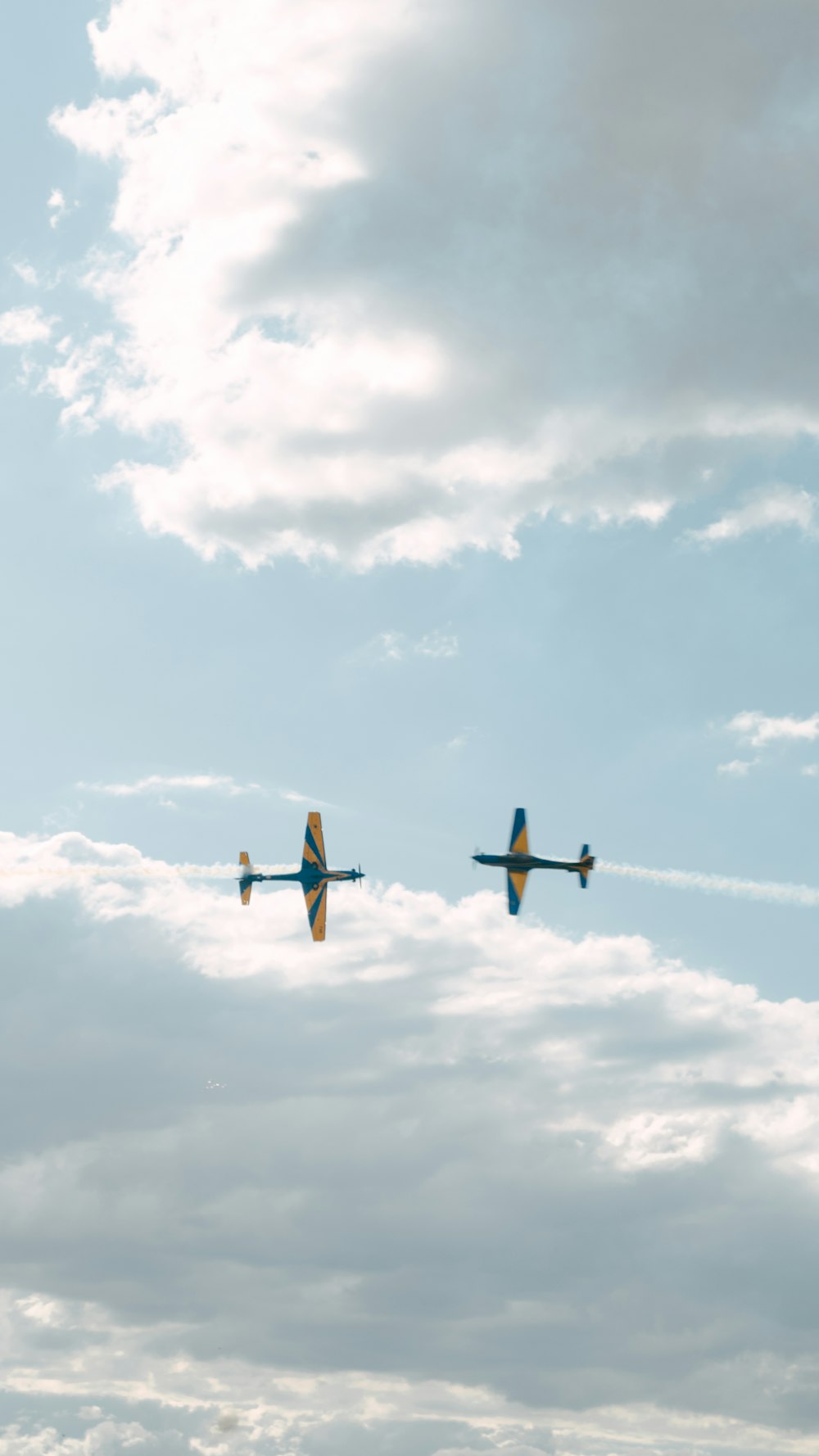 two planes flying in the sky with clouds in the background