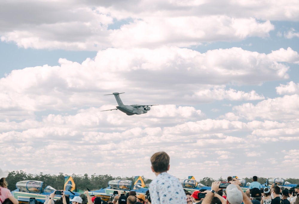 a crowd of people watching a plane fly overhead