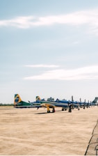 A lively outdoor ULM meeting with colorful aircrafts lined up under a bright blue sky.