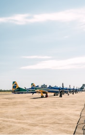 A lively outdoor ULM meeting with colorful aircrafts lined up under a bright blue sky.