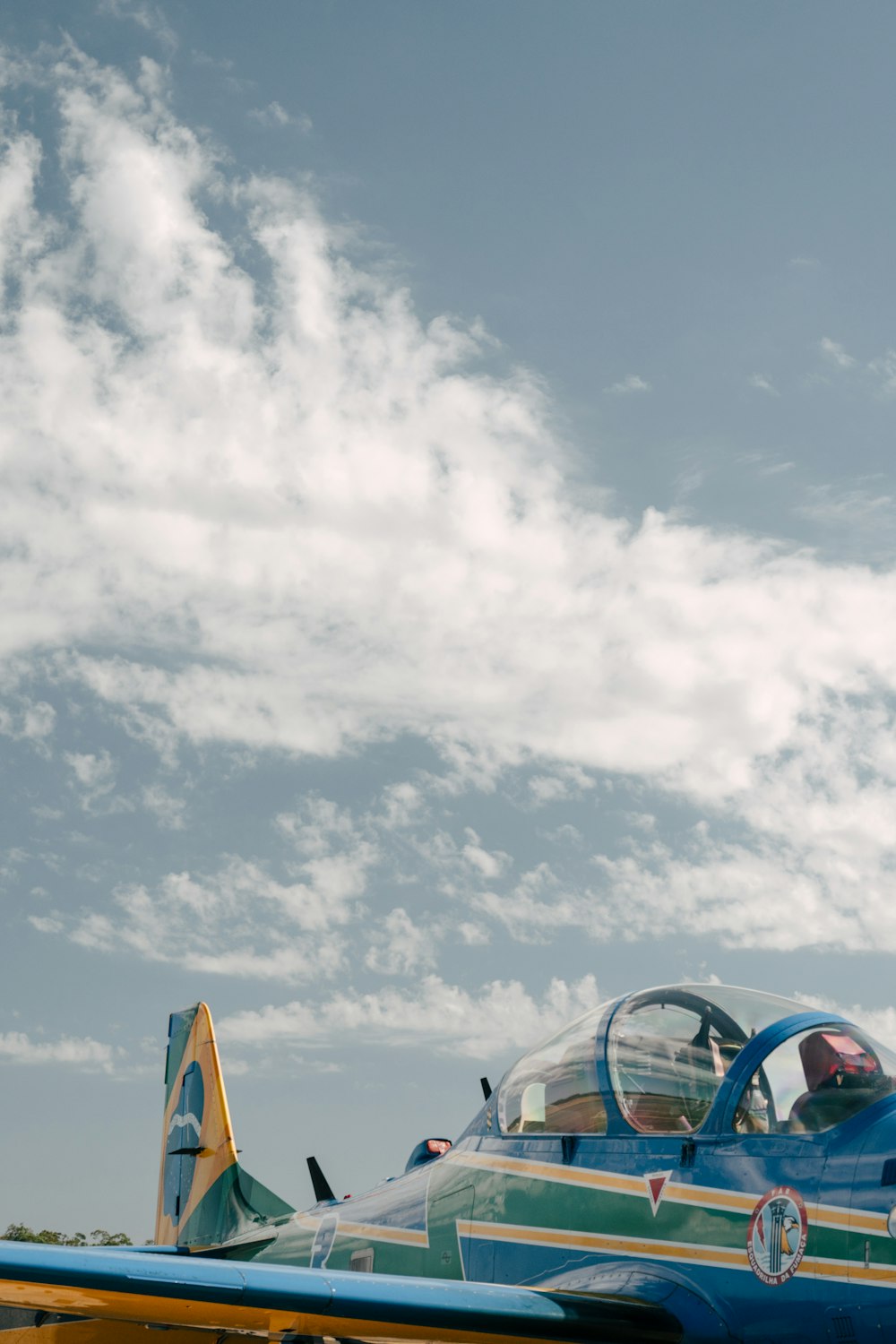 a blue and yellow airplane with a pilot in the cockpit