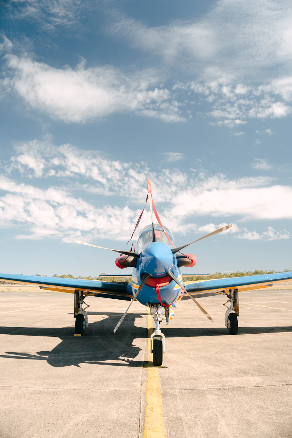 Small blue and red airplane parked on an airfield with nose pointing upwards slightly