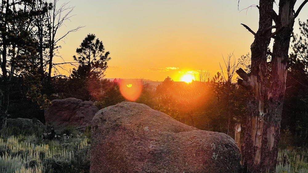 the sun is setting over a rocky outcropping