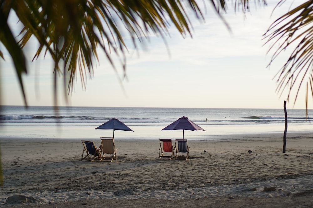 two beach chairs with umbrellas on a beach