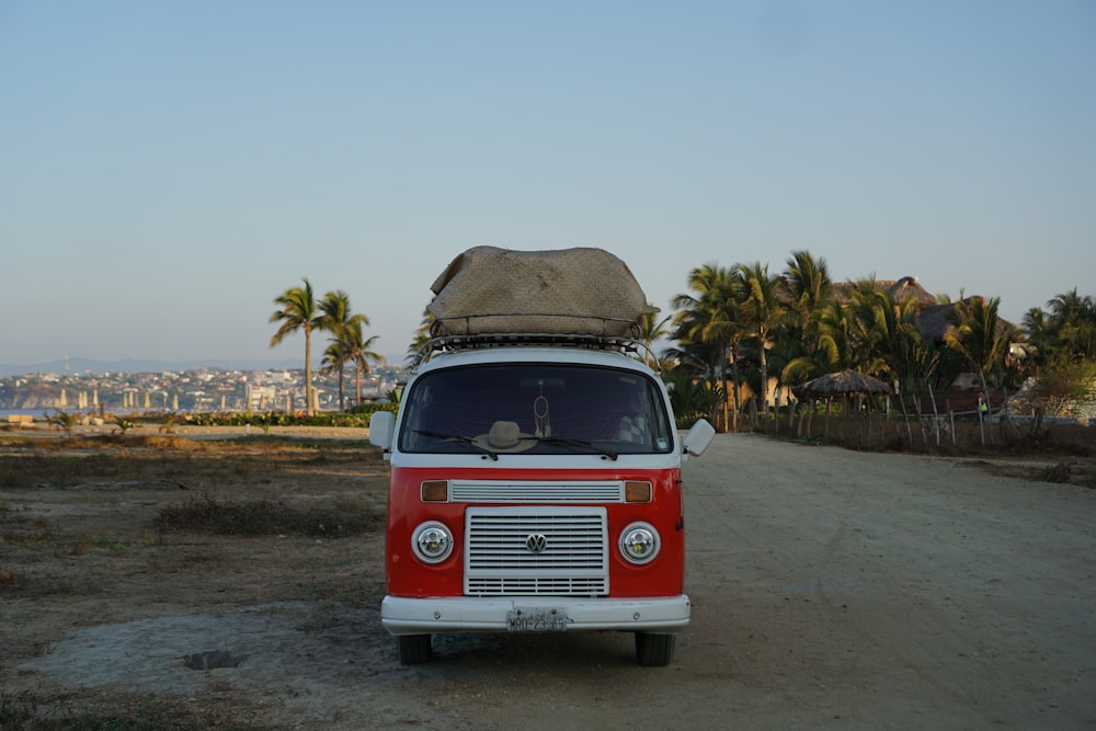 a red and white van parked on a dirt road