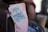 A close-up of a coffee bag with a label attached by a clip. The label features a cloud illustration with a crescent moon and wavy lines, reading 'Urban Cloud Coffee Roasters' and location details in stylized text. The image is softly lit, with some blurred objects in the background.