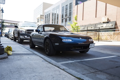 A sleek Irishcorktaxi car waiting outside a busy Cork city street at dusk.