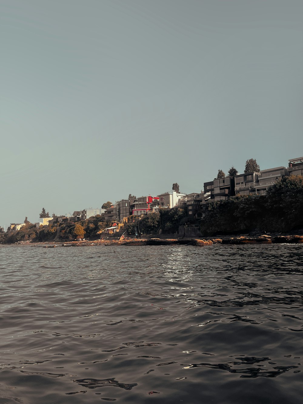 a body of water with houses on a hill in the background