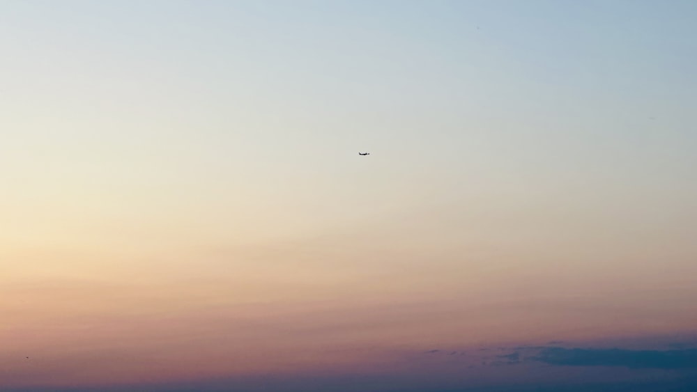 ein Flugzeug, das bei Sonnenuntergang am Himmel fliegt