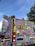A vibrant and elaborately painted food truck with detailed artwork covering its surface. The designs include floral patterns, decorative elements, and a label reading 'FOOD TRUCK' in bold letters. There is also a sign with 'TRUCK WALL THE SPICY TRAILER' and a colorful mural featuring landscapes and intricate designs.