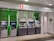 A row of five automated teller machines (ATMs) are stationed under a sign that reads 'Hang Seng Bank.' The machines have various interfaces and screens, with some displaying different languages and services. One of the machines has a sign indicating foreign exchange withdrawal. The area around the machines is clean and well-lit.