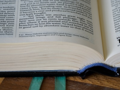 An open ancient manuscript displaying Aramaic grammar notes with a quill pen beside it