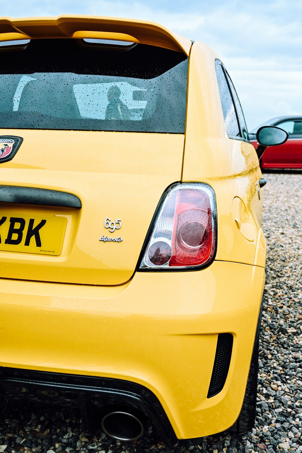 a yellow sports car parked in a gravel parking lot