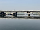A freshly paved bridge with smooth black asphalt stretching over a river.