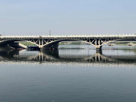 A freshly paved bridge with smooth black asphalt stretching over a river.
