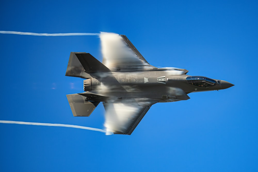 a fighter jet flying through a blue sky