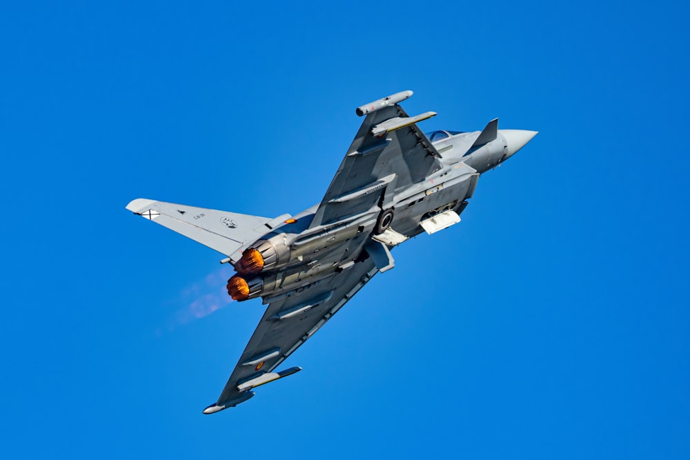 a fighter jet flying through a blue sky