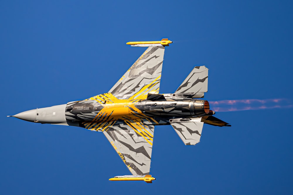 a fighter jet flying through a blue sky