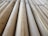 A close-up view of several bamboo sticks arranged parallel to each other, displaying a range of light brown and beige shades with visible natural textures and grains.