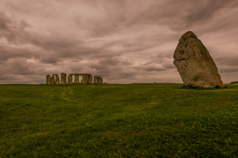 a large rock in the middle of a grassy field