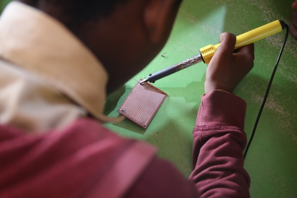An engineer soldering components onto a prototype board in a bright workspace.