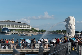 a crowd of people standing on a pier next to a body of water