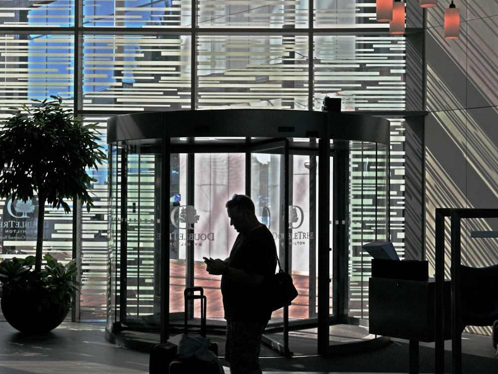 a man standing in front of a tall glass building