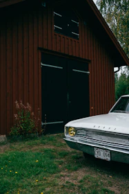 a white car parked in front of a red barn