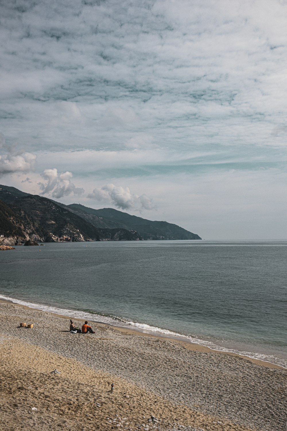 a group of people sitting on top of a sandy beach