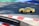 A yellow sports car with the marking 'MASTERDRIVE' on its side is navigating a racing track. The track is marked with red and white curbs, and there is a section of green and blue in the background. Shadows are cast onto the track surface, suggesting bright sunlight.