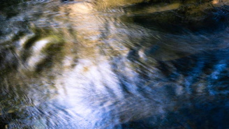 A serene image of flowing water illuminated by soft blue and magenta lights symbolizing vibrational energy.