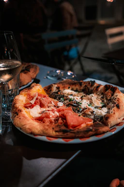 A cozy restaurant table set with a steaming plate of Margherita pizza and a glass of red wine, bathed in warm ambient light.