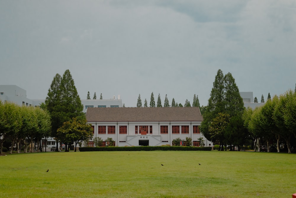 a white building with red shutters and trees in front of it