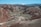 A foothills vista with layered sagebrush and charcoal-gray rocky outcrops beneath a clear blue sky.