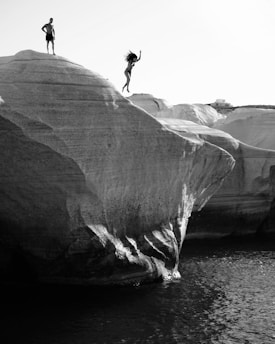 Black and white dynamic group photo of the verticalvoid French rope jump team mid-bungee jump, with Pyrenean mountains and cliffs in the background, showing youthful energy and teamwork, slightly grainy like a sports report, featuring a subtle French record medal.