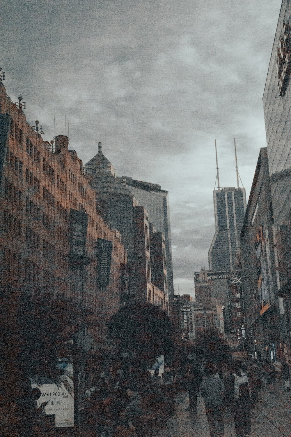 a group of people walking down a street next to tall buildings