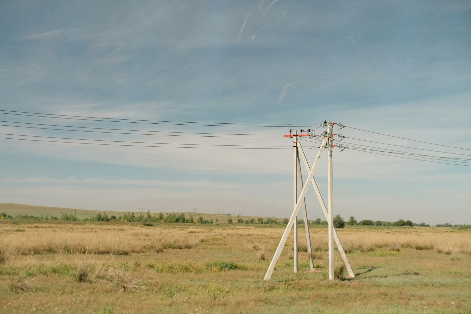 a field with power lines and a telephone pole