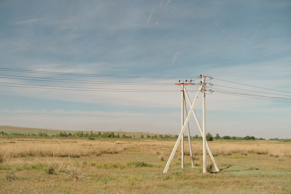 a field with power lines and a telephone pole