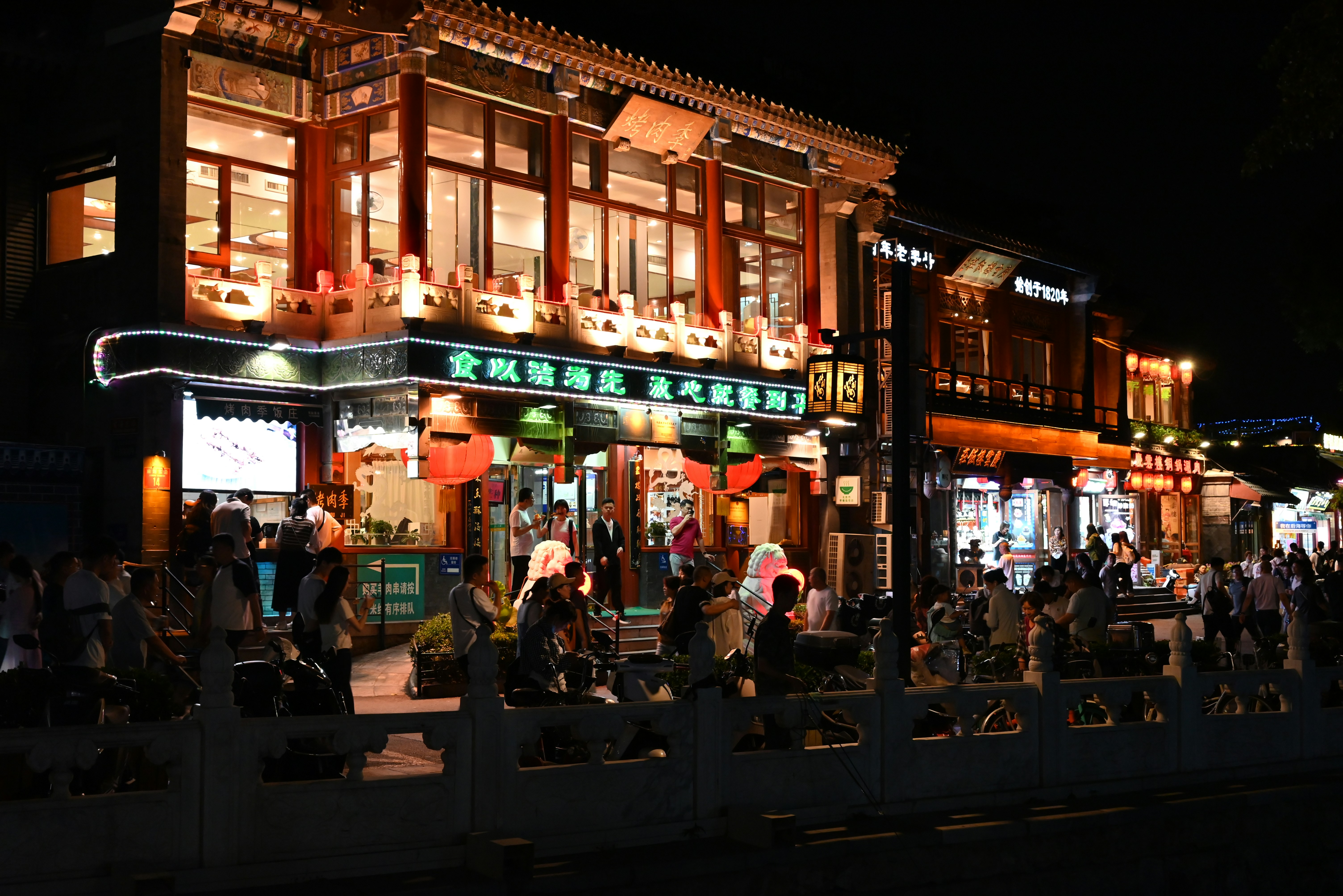 a group of people walking down a street at night