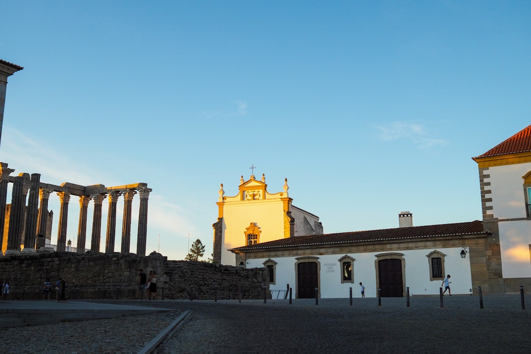a building with columns and a clock tower in the background,
