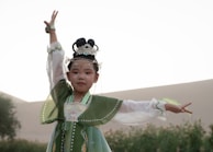 A young girl wearing a beautiful dress, preparing for her bat mitzvah with a volunteer’s gentle help.