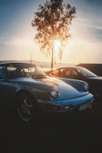 A sunset silhouette of a classic convertible parked by a quiet street.