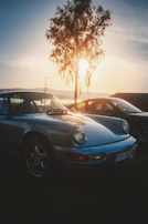 Side view of a classic car with soft charcoal and cream color palette under warm sunlight.