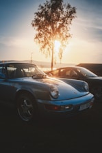 A classic sports car parked against a vibrant sunset backdrop.