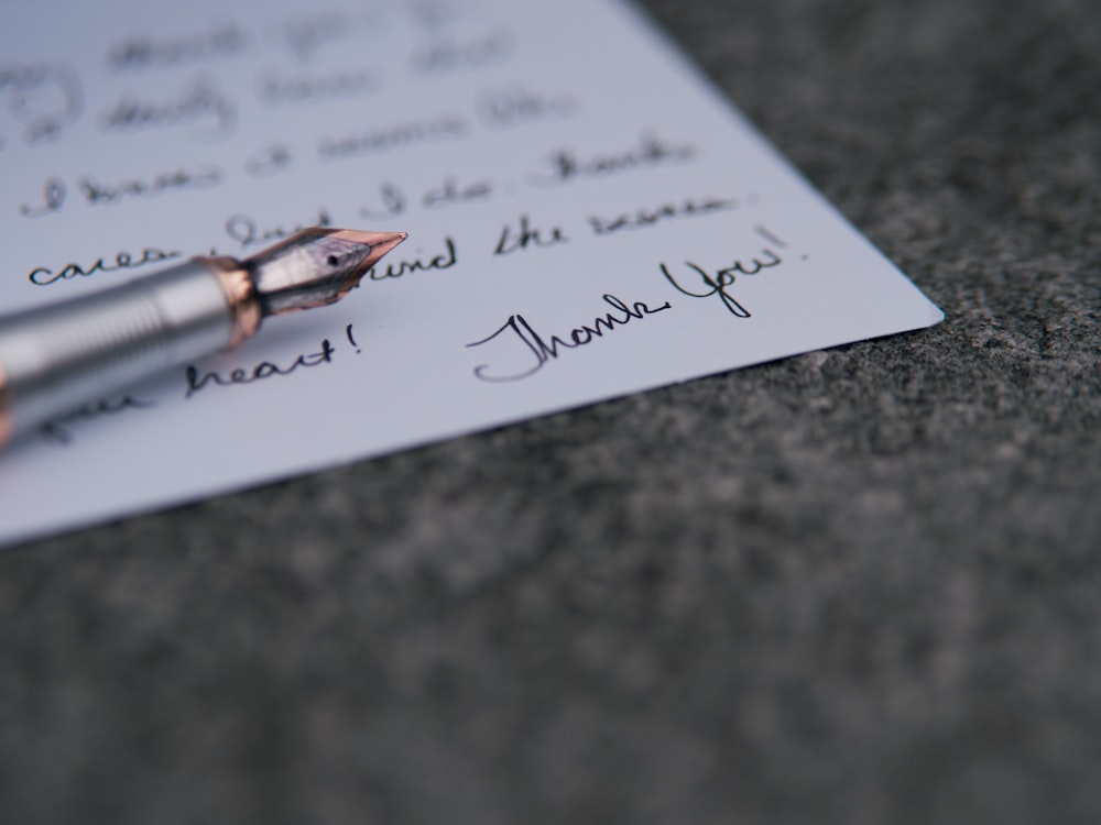 una penna sopra un pezzo di carta con scritto su di esso
