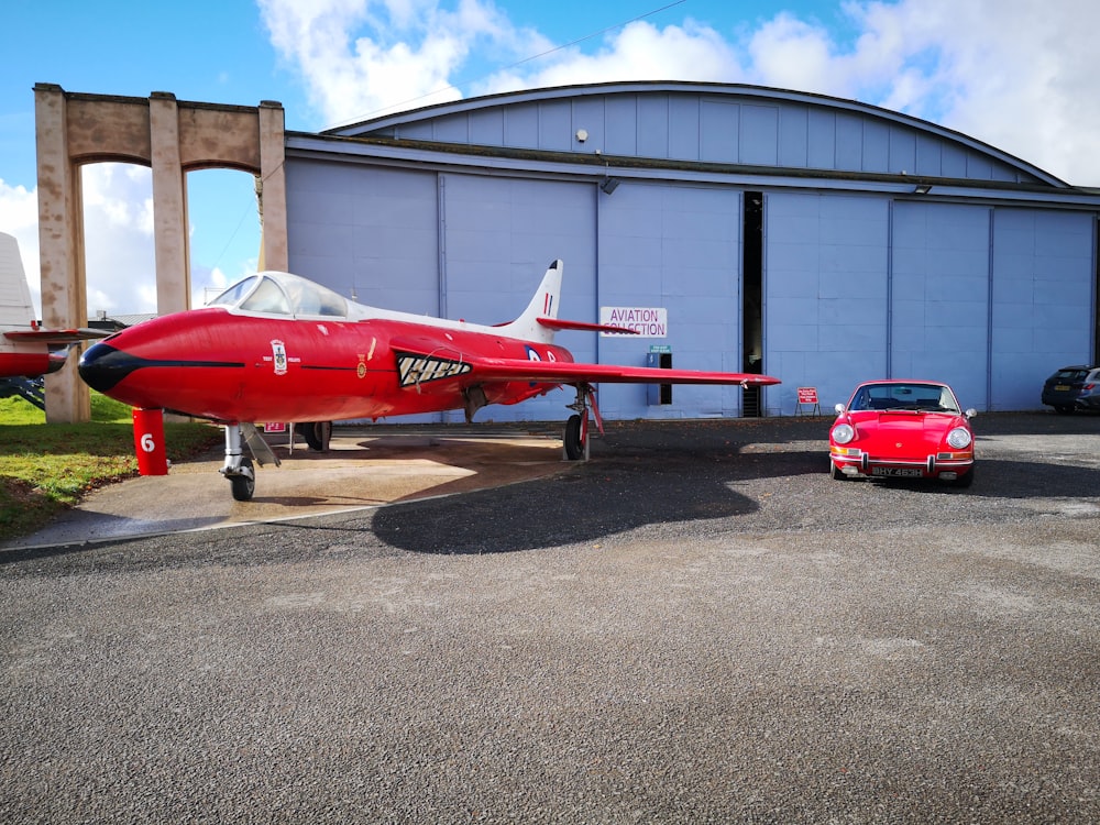 a red airplane parked next to a red car