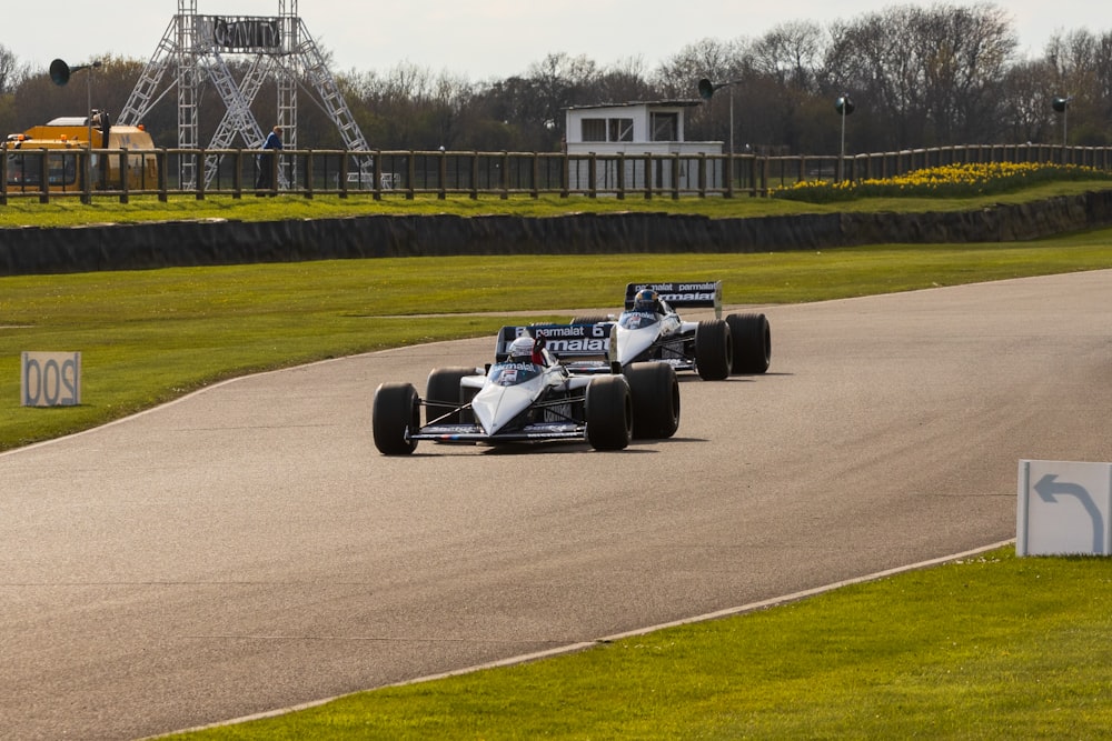 a couple of racing cars driving down a race track